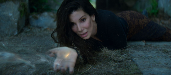 Sandra Bullock lays on the ground with her arm outstretched in a still from the movie Practical Magic 2.